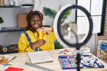 Foto de African american woman artist recording video showing pencils at art studio - Imagen libre de derechos