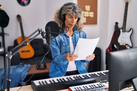 Photo for Middle age woman singer singing song at music studio - Royalty Free Image