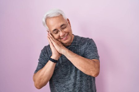 Photo for Middle age man with grey hair standing over pink background sleeping tired dreaming and posing with hands together while smiling with closed eyes. - Royalty Free Image