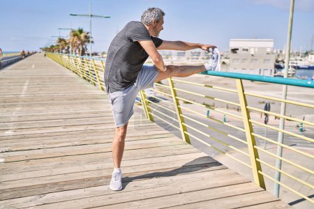 Photo for Middle age hispanic man wearing sportswear stretching at street - Royalty Free Image