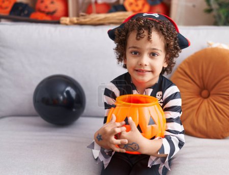 Photo for Adorable hispanic boy having halloween party holding pumpkin basket at home - Royalty Free Image