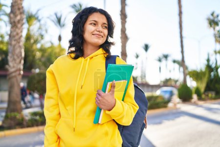 Photo for Young latin woman student smiling confident holding books at street - Royalty Free Image