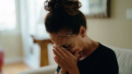 Photo for Middle age hispanic woman suffering for domestic violence with bruise on eyes crying at home - Royalty Free Image