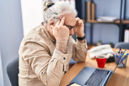 Téléchargez les photos : Moyen âge homme aux cheveux gris travailleur d'affaires stressé à l'aide d'un ordinateur portable au bureau - en image libre de droit