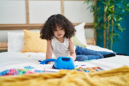Téléchargez les photos : Enfant afro-américain jouant avec un jouet téléphonique assis sur le lit dans la chambre - en image libre de droit