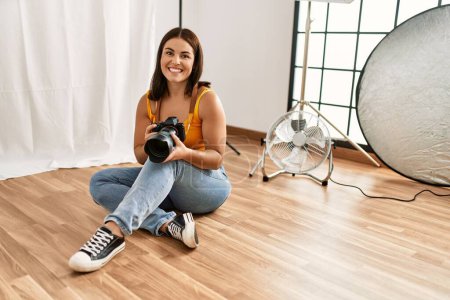 Téléchargez les photos : Jeune belle femme hispanique photographe tenant studio photo appareil photo professionnel - en image libre de droit