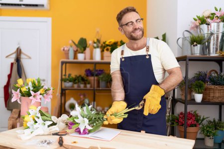 Téléchargez les photos : Middle age man florist smiling confident cutting stem plant at flower shop - en image libre de droit