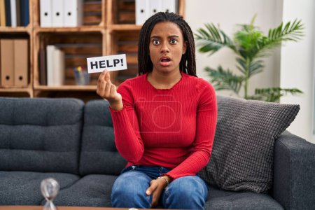 Photo for Young african american with braids doing therapy holding help banner scared and amazed with open mouth for surprise, disbelief face - Royalty Free Image