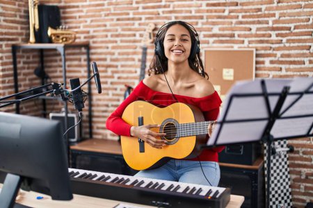 Photo for Young african american woman musician playing classical guitar at music studio - Royalty Free Image