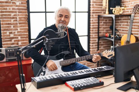 Foto de Músico hombre de pelo gris de mediana edad cantando canción tocando la guitarra eléctrica en el estudio de música - Imagen libre de derechos
