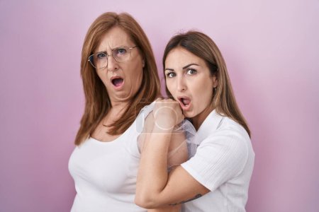 Téléchargez les photos : Mère et fille hispaniques portant un t-shirt blanc décontracté au visage choqué, à l'air sceptique et sarcastique, surpris par la bouche ouverte - en image libre de droit