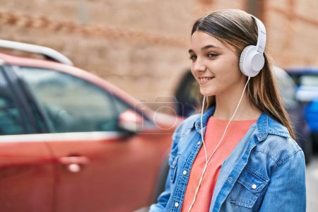 Photo for Adorable girl listening to music and dancing at street - Royalty Free Image