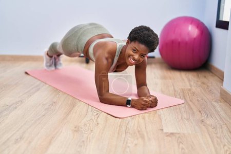 Téléchargez les photos : Afro-américaine femme souriant entraînement confiant abs exercice au centre sportif - en image libre de droit