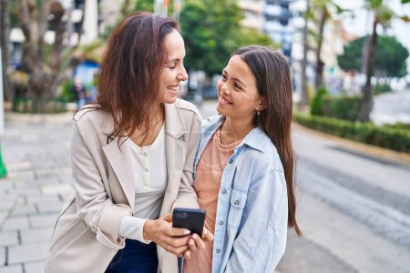 Photo for Woman and girl mother and daughter using smartphone at street - Royalty Free Image