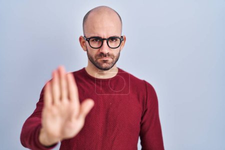 Téléchargez les photos : Young bald man with beard standing over white background wearing glasses doing stop sing with palm of the hand. warning expression with negative and serious gesture on the face. - en image libre de droit