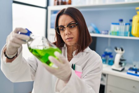 Téléchargez les photos : Young beautiful hispanic woman scientist measuring liquid at laboratory - en image libre de droit