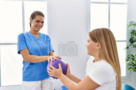 Téléchargez les photos : Physiothérapeute femme et fille et patiente en cure de désintoxication utilisant le ballon à la clinique de physiothérapie - en image libre de droit