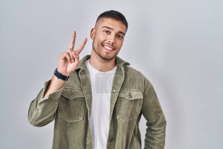 Photo for Young hispanic man standing over isolated background smiling looking to the camera showing fingers doing victory sign. number two. - Royalty Free Image