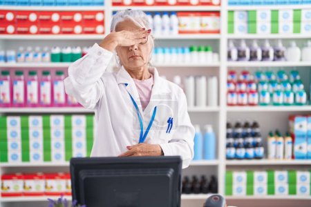 Foto de Middle age woman with tattoos working at pharmacy drugstore covering eyes with hand, looking serious and sad. sightless, hiding and rejection concept - Imagen libre de derechos