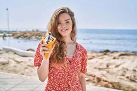 Foto de Young caucasian girl smiling confident eating ice cream at seaside - Imagen libre de derechos