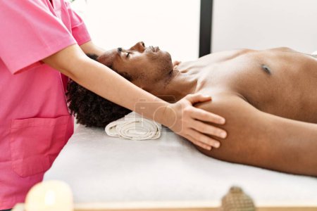 Foto de Joven afroamericano hombre teniendo hombros masaje en centro de belleza - Imagen libre de derechos