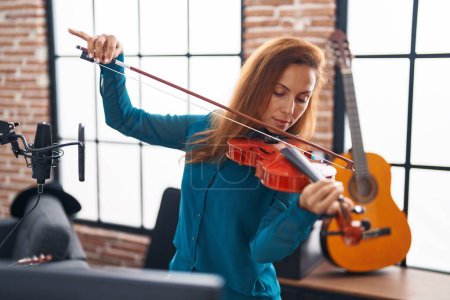 Foto de Young woman musician playing violin at music studio - Imagen libre de derechos