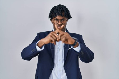 Foto de Joven africano con rastas usando chaqueta de negocios sobre fondo blanco expresión de rechazo cruzando dedos haciendo signo negativo - Imagen libre de derechos
