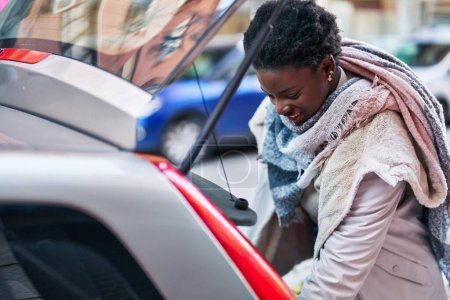 Téléchargez les photos : African american woman smiling confident opening car trunk door at street - en image libre de droit