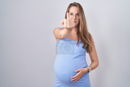 Foto de Young pregnant woman standing over white background showing middle finger, impolite and rude fuck off expression - Imagen libre de derechos