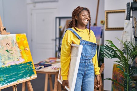 Foto de Mujer afroamericana artista sonriendo confiado sosteniendo dibujo en el estudio de arte - Imagen libre de derechos