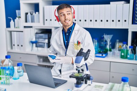 Photo for Young hispanic man scientist using laptop and smartphone at laboratory - Royalty Free Image