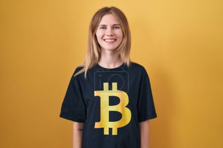 Téléchargez les photos : Blonde caucasian woman wearing bitcoin t shirt with a happy and cool smile on face. lucky person. - en image libre de droit