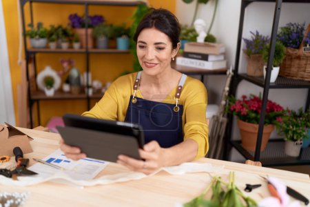 Photo for Middle age hispanic woman florist smiling confident using touchpad at flower shop - Royalty Free Image