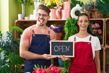 Photo for Young hispanic man a woman working at florist holding open sign winking looking at the camera with sexy expression, cheerful and happy face. - Royalty Free Image