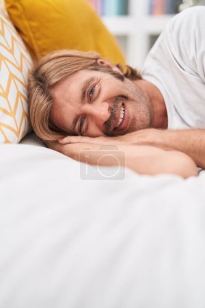 Téléchargez les photos : Young blond man smiling confident lying on bed at bedroom - en image libre de droit