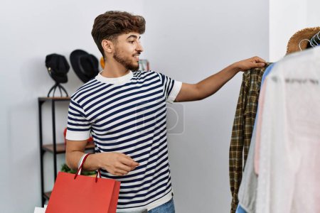 Photo for Young arab man customer smiling confident shopping at clothing store - Royalty Free Image