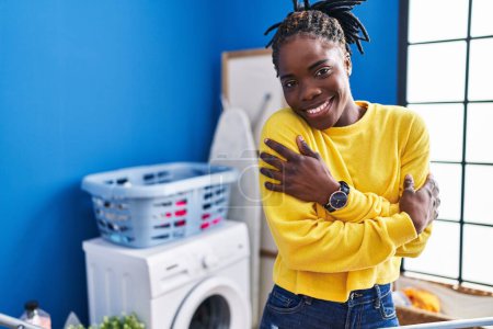 Téléchargez les photos : African american woman hugging himself hanging clothes on clothesline at laundry room - en image libre de droit