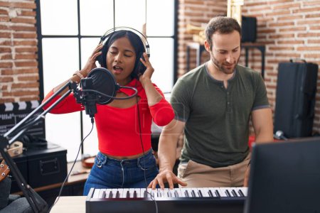 Téléchargez les photos : Man and woman musicians singing song playing piano at music studio - en image libre de droit