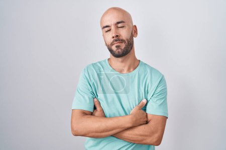 Foto de Middle age bald man standing over white background looking sleepy and tired, exhausted for fatigue and hangover, lazy eyes in the morning. - Imagen libre de derechos