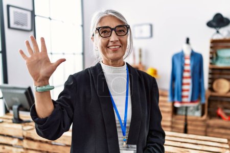 Photo for Middle age grey-haired woman working as manager at retail boutique showing and pointing up with fingers number five while smiling confident and happy. - Royalty Free Image