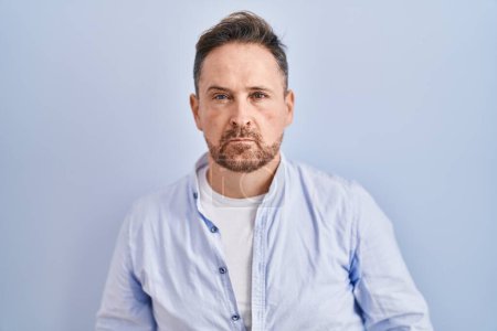 Photo for Middle age caucasian man standing over blue background skeptic and nervous, frowning upset because of problem. negative person. - Royalty Free Image