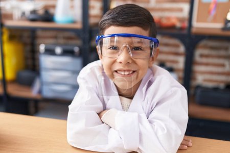 Photo for Adorable hispanic boy student leaning on table with arms crossed gesture at laboratory classroom - Royalty Free Image