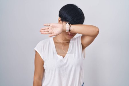 Foto de Young asian woman with short hair standing over isolated background covering eyes with arm, looking serious and sad. sightless, hiding and rejection concept - Imagen libre de derechos