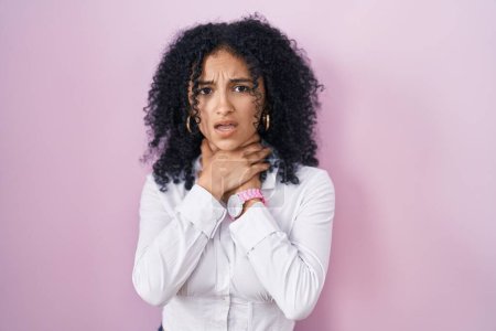 Photo for Hispanic woman with curly hair standing over pink background shouting suffocate because painful strangle. health problem. asphyxiate and suicide concept. - Royalty Free Image