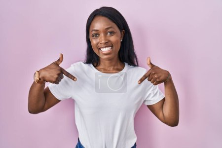 Photo for African young woman wearing casual white t shirt looking confident with smile on face, pointing oneself with fingers proud and happy. - Royalty Free Image