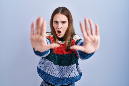 Photo for Young hispanic girl standing over blue background doing stop gesture with hands palms, angry and frustration expression - Royalty Free Image