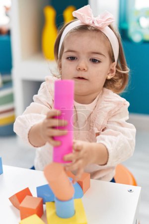Photo for Adorable blonde toddler playing with construction blocks standing at kindergarten - Royalty Free Image