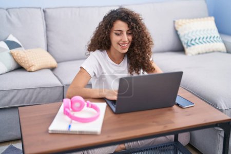 Photo for Young beautiful hispanic woman using laptop sitting on floor studying at home - Royalty Free Image