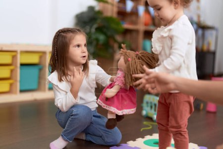 Foto de Dos niñas jugando con muñecas sentadas en el suelo en el jardín de infantes - Imagen libre de derechos