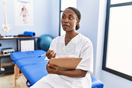 Téléchargez les photos : African american woman physiotherapist smiling confident speaking at rehab clinic - en image libre de droit